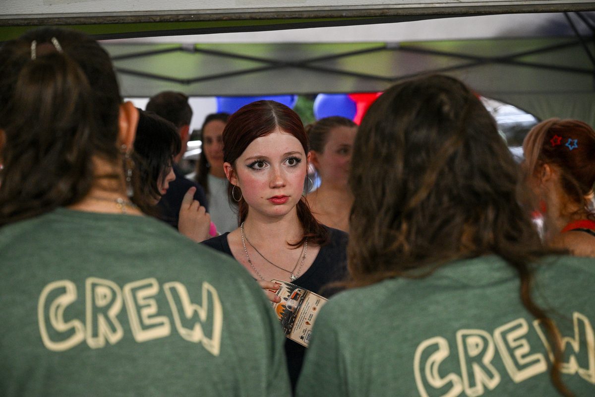 Twin City Silver Bullet crew members in green crew shirts gathered under the tent between orders.