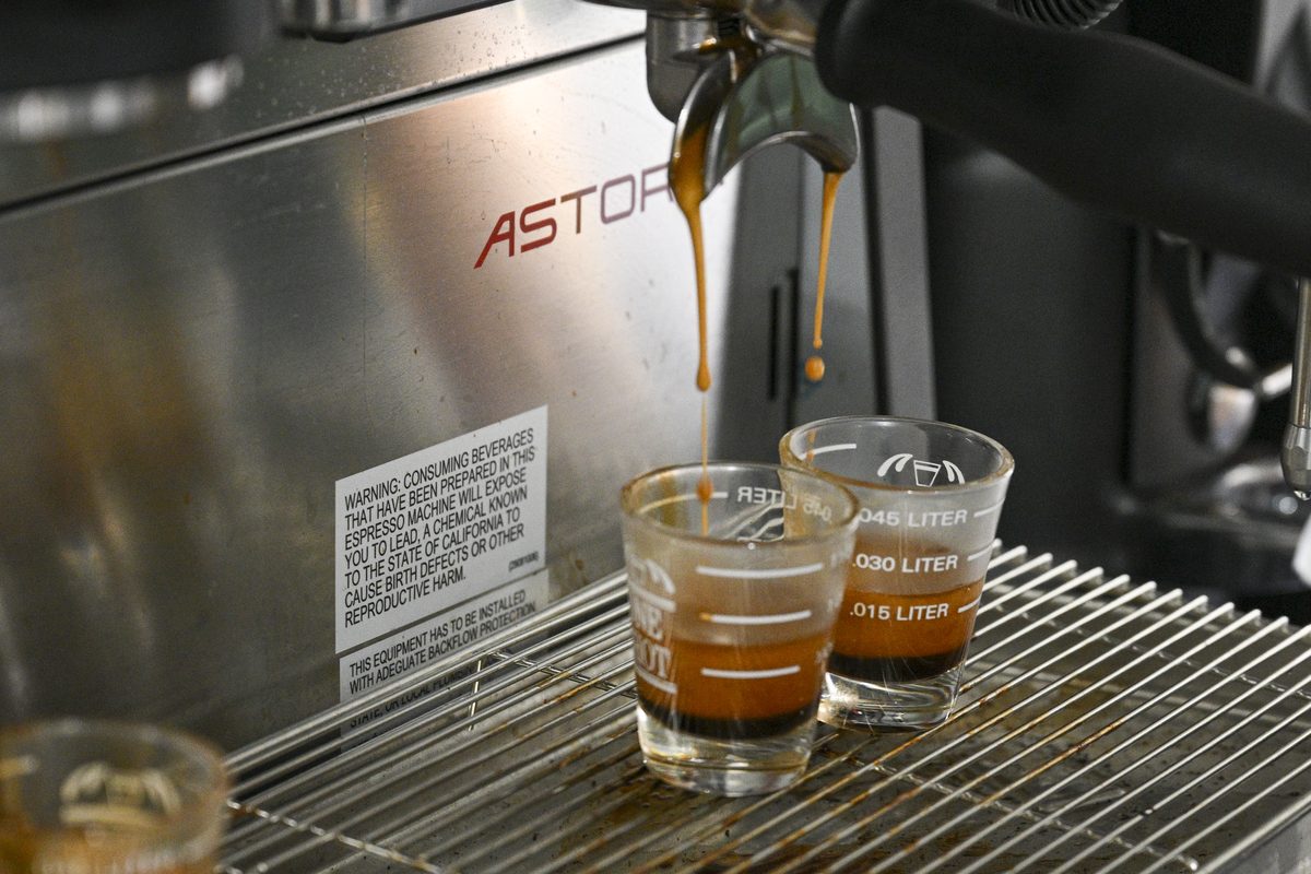 Two shots of espresso pulling into glass measuring cups on the espresso machine.